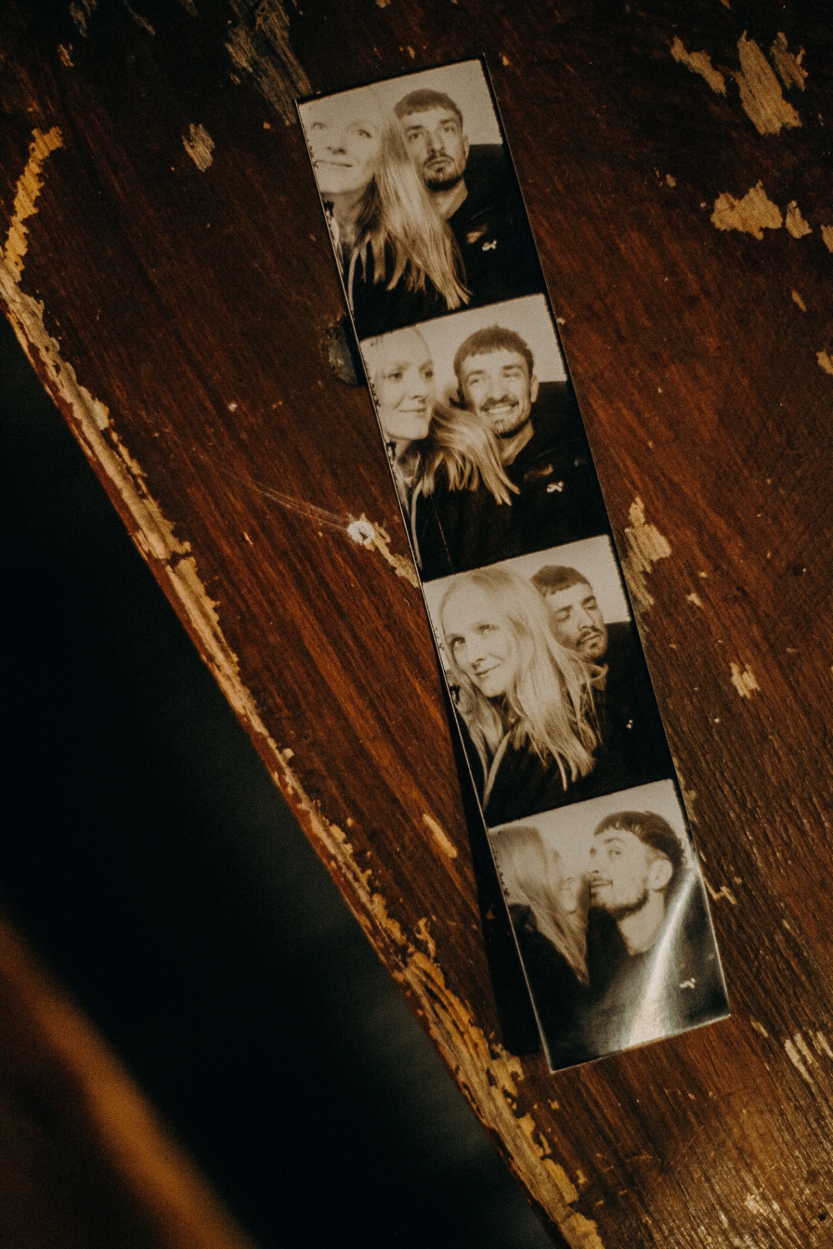Sepia photobooth strip resting on a worn wooden table
